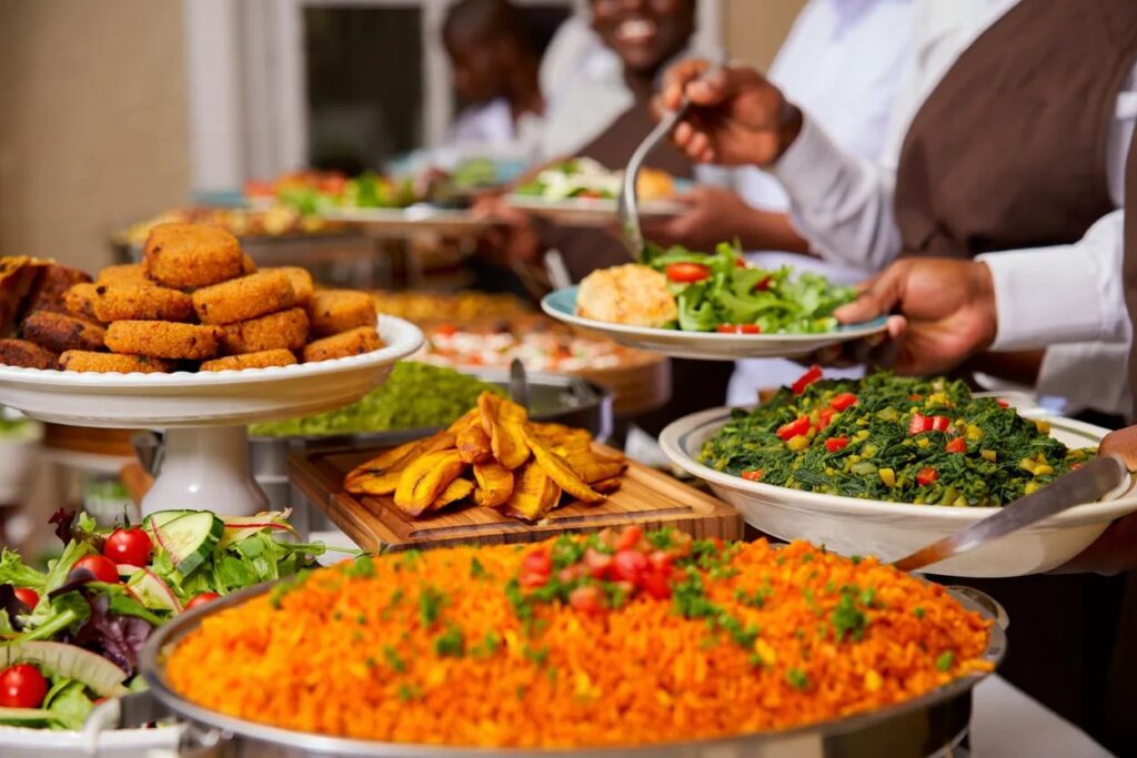 Nigerian catering buffet with rice plantain and vegetable dishes